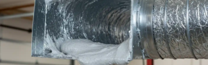 Technician performing aerosealing ductwork and energy assessment in a residential home HVAC system